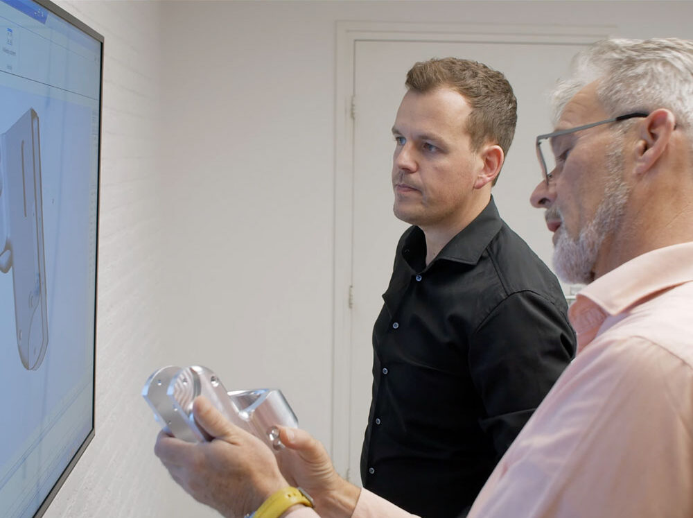 Twee medewerkers van Pillen Group staand voor een scherm in overleg over een productonderzoek.